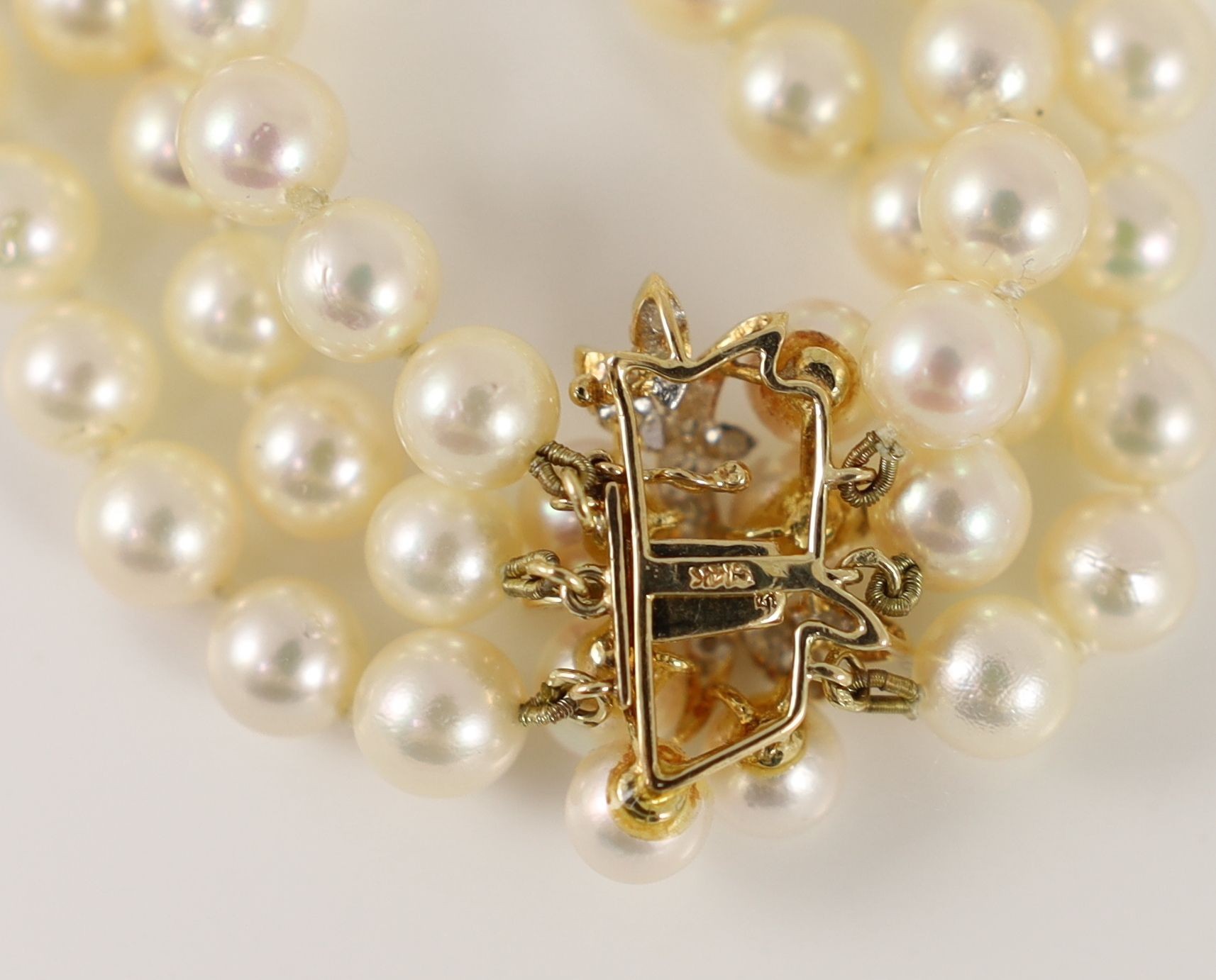 A modern triple strand cultured pearl necklace, with a 14k gold, cultured pearl and diamond set clasp